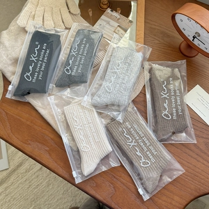 Detail of 6 pairs of wool socks in neutral tones with individual zipper bags on wooden table