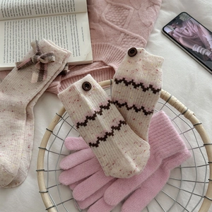 Detailed knit wool arm warmers with wooden buttons and pink gloves in a cozy setting