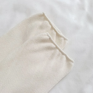 Dettaglio ravvicinato di calze a maglia color crema con design minimalista a bordo arrotolato