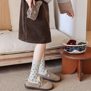 Detail of wool socks with polka dots and deer embroidery worn with cozy mules