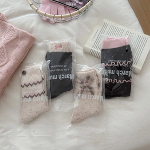 Detail view of wool socks with ruffles, bows, and buttons in pink and black colors