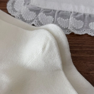 Détail macro de chaussettes en tricot crème avec broderie cœur sur bordure en dentelle