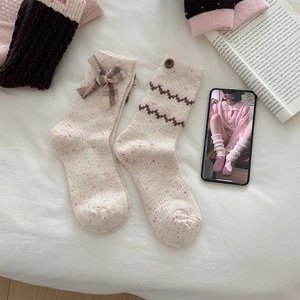 Detailed close-up of wool knit socks with decorative bows and buttons on a soft background