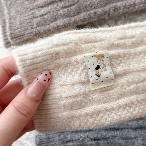 Close-up of ribbed knit wool arm warmers with a cute puppy patch in neutral colors