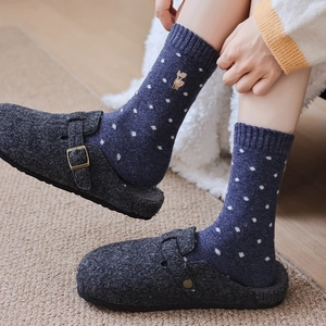 Close-up of navy blue wool socks with white polka dots and deer embroidery in grey clogs