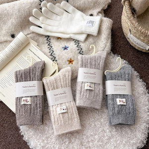 Detail view of thick winter wool socks and knit gloves on a cozy white faux fur rug