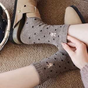 Close-up of wool socks with polka dots and alpaca embroidery on warm knit fabric