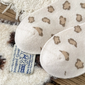 Macro view of vintage leopard print knit socks with branded fabric label and soft wool texture