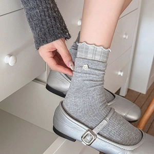 Détail de chaussettes grises en tricot avec bordure à carreaux et boutons floraux