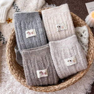 Close-up of thick knitted wool socks with cute dog patches in a cozy wicker basket