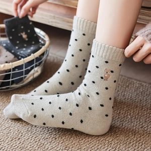 Detail of wool socks featuring cute alpaca embroidery and vintage black polka dots