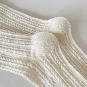 Dettaglio della maglia a trecce spessa su calze di lana color crema per l'inverno