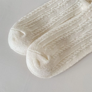 Dettaglio macro di calze in lana bianco crema con trama a trecce e finitura a costine