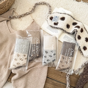 Flat lay of four pairs of vintage leopard patchwork socks in neutral tones with packaging