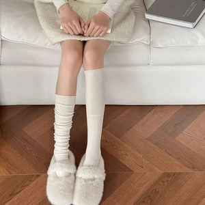 Dettaglio di calze al polpaccio in maglia a coste crema con morbide pantofole in peluche