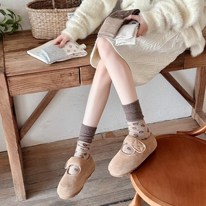 Detail of knitted mid-tube socks featuring brown hearts and ribbed cuffs with Mary Janes