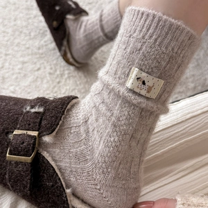 Close-up of oatmeal wool socks featuring a cute puppy label and cozy knit texture