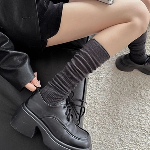 Dettaglio di calze a costine grigio scuro arricciate con scarpe nere platform
