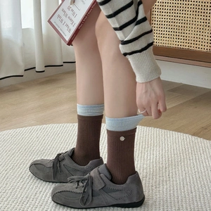 Striped knit crew socks with button detail and ribbed cuffs worn with casual shoes