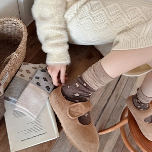 Detail of vintage leopard print socks paired with brown suede Mary Jane shoes on wood floor
