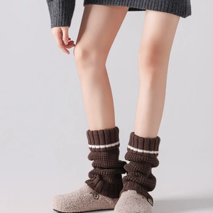 Detailed texture of thick dark brown knitted leg warmers with white striped trim