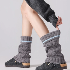 Detailed texture of thick knit leg warmers with blue stripes in dark grey wool
