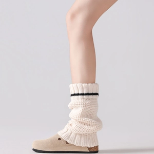 Close-up of thick beige knitted leg warmers with black stripes and wool-like texture