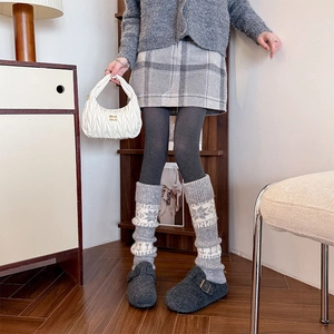 Detailed view of grey knitted leg warmers with snowflake patterns and retro winter styling