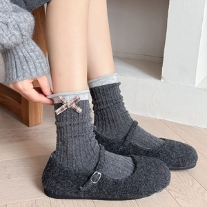 Dettaglio delle calze di lana con fiocco a quadretti vintage e motivo a maglia a coste