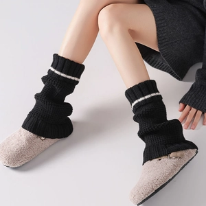 Detail of black knitted leg warmers with white stripes and ribbed texture material