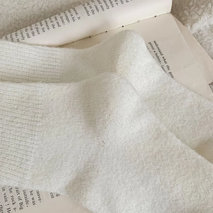 Detailaufnahme weißer Wollstricksocken mit weicher Textur und vertikalem Rippenstrickmuster
