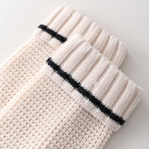 Close-up of thick knit leg warmer featuring ribbed cuff and black contrast stripe detail