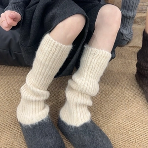 Close-up of cream white thick ribbed knit leg warmers showing soft wool texture details