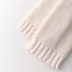 Detail of cream knit leg warmer showing hollow mesh texture and ribbed cuff design
