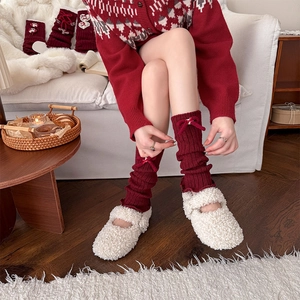 Detail of red knit leg warmers with ribbon bows and pearls for winter ballet style