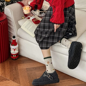 Détail hivernal de chaussettes en laine à broderie pain d'épice et mules en peluche