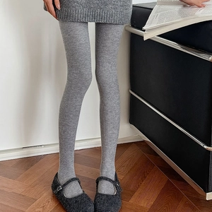 Close-up of grey vertical striped wool leggings paired with black Mary Jane shoes