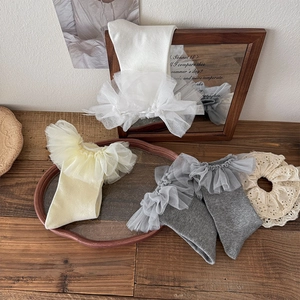 Sweet Lolita ruffle lace ankle socks in white, pale yellow, and grey on wood surface