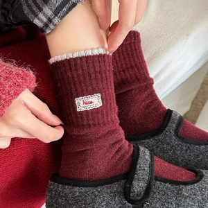 Detailed knit texture of wool socks featuring a red velvet bow and 'Nice' embroidery