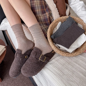 Cozy autumn look featuring brown felt clogs and beige ribbed socks in a warm home setting