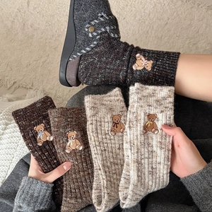 Detail of thick knit crew socks with cute bear embroidery and ribbed texture in brown tones