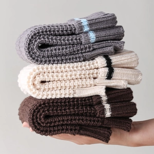Macro detail of thick knitted leg warmers with contrast stripes and waffle texture