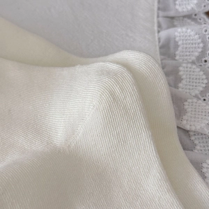 Macro trama di cotone bianco lavorato a maglia e dettagli in pizzo di un calzino casual