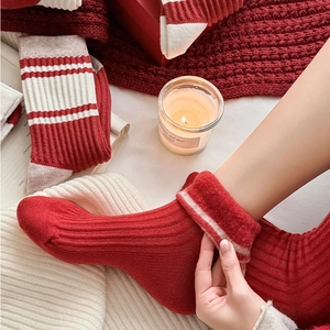 Detail of red and cream striped knitted socks featuring warm ribbed texture and folded cuffs