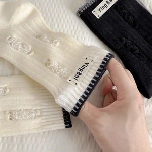 Detail view of vintage wool socks with distressed hole design and Ying Bai logo label