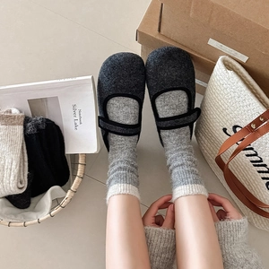 Close-up of thick knitted winter socks paired with gray felt Mary Jane home slippers