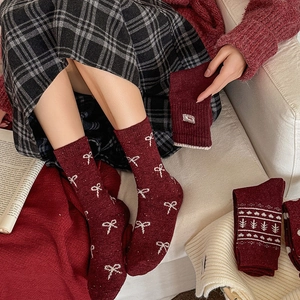 Close-up of wool socks with festive red velvet bow and white jacquard holiday patterns