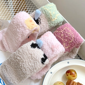 Close-up of thick coral fleece socks with cartoon pig motifs in assorted pastel colors