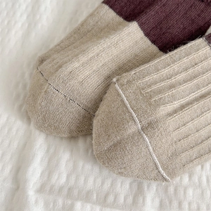 Macro view of beige and burgundy knitted wool socks with reinforced toe stitching