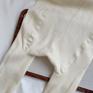 Detail of cream rib-knit leggings showing crotch seam construction and elastic texture